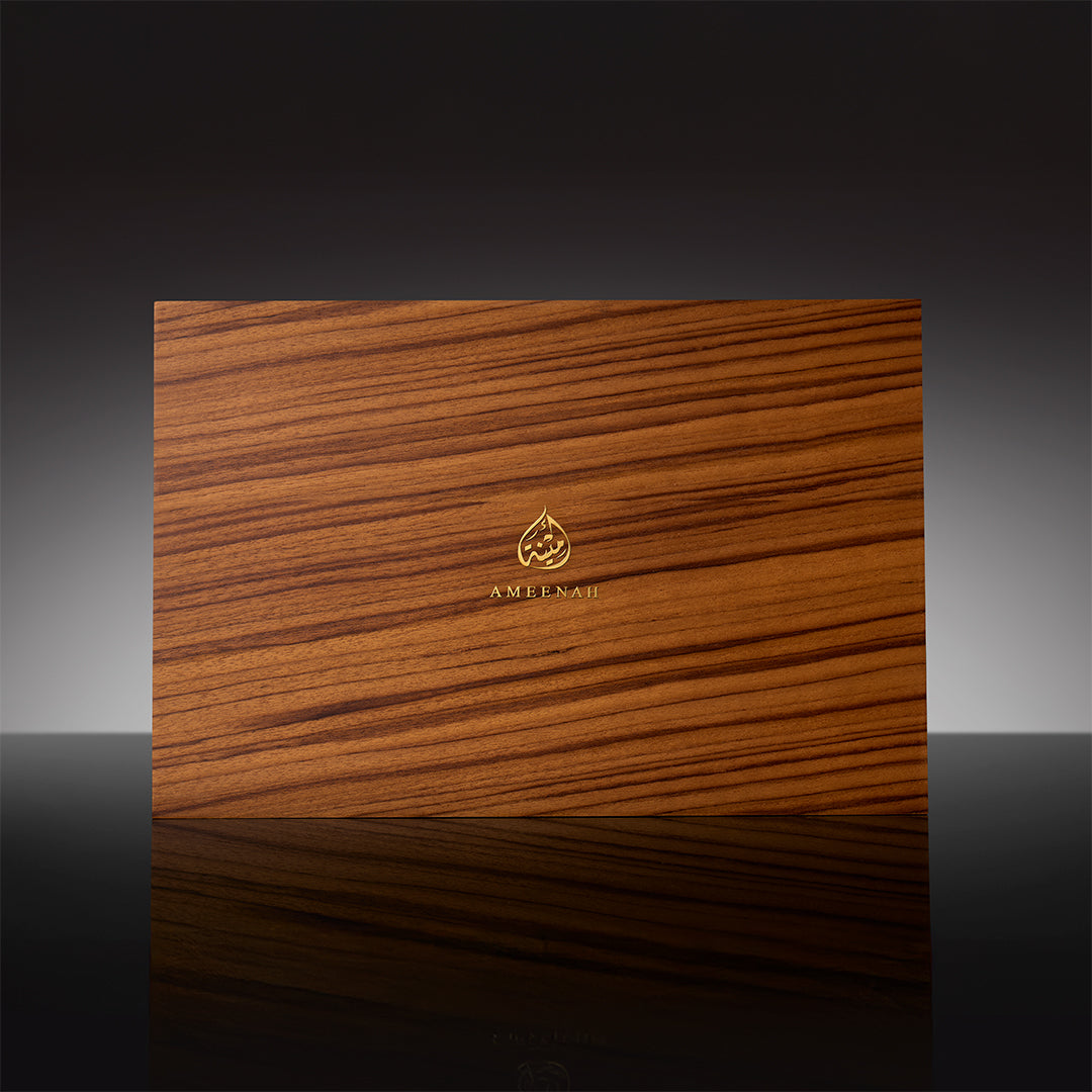 A three-slot Prestige Gift Set wooden box containing Ameenah perfumes and oud oils displayed on a dark velvet base.